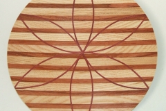 A laminated shallow plate made from 3 woods, the horizontal stripes are Ash and Myrtle and the petal shapes are Mahogany.